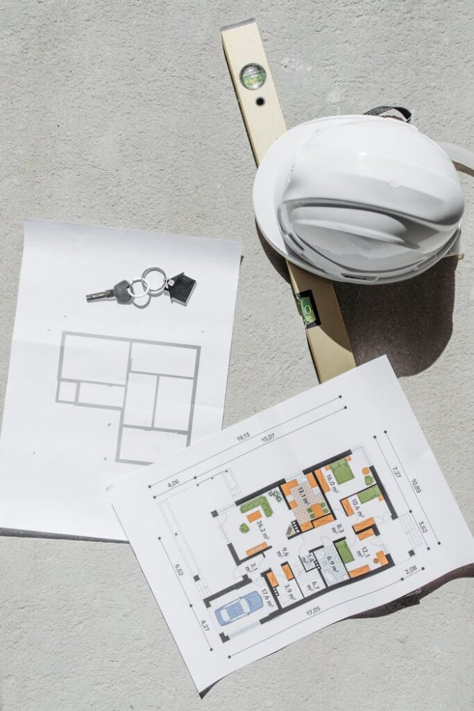 The Art of Drawing Readers In: Your attractive post title goes here Flat lay of construction plans, keys, hard hat, and level tool on concrete.